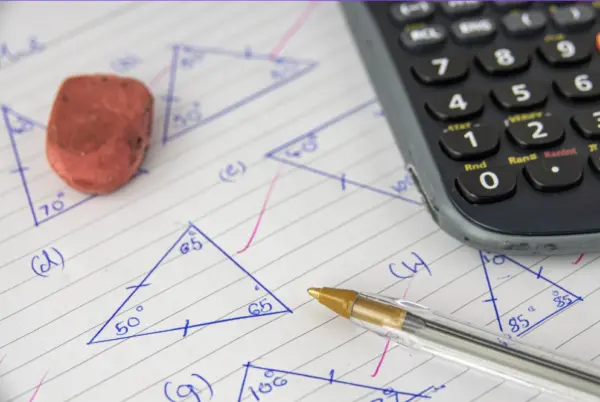 A pen, calculator, pen, and used eraser on top of a math homework sheet.