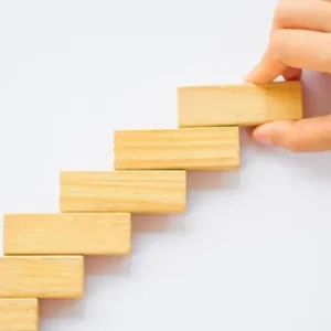 Stack of wooden blocks being placed by a hand in staircase formation.